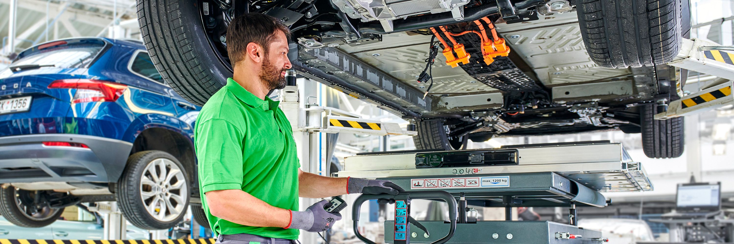 Ein Škoda Mechaniker beim Austausch einer Elektroauto Batterie.